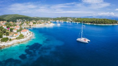 Mavi denizde yelkenli tekne Yunanistan 'ın Kefalonia adasındaki Fiscardo köyüne vardı.
