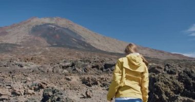 Teide, Tenerife, Kanarya Adaları, İspanya. Genç bir kadın volkanik kum boyunca volkanik volkan kraterinde lav kayaları arasında yürüyüş yapıyor..