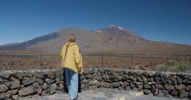 Teide, Tenerife, Kanarya Adaları, İspanya. Genç bir kadın volkanik kum boyunca volkanik volkan kraterinde lav kayaları arasında yürüyüş yapıyor.