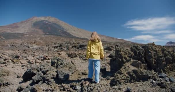 Teide, Teneryfa, Wyspy Kanaryjskie, Hiszpania. Młoda kobieta wędrująca wzdłuż wulkanicznego piasku pośród skał lawy w ogromnym kraterze wulkanu Teide — Wideo stockowe