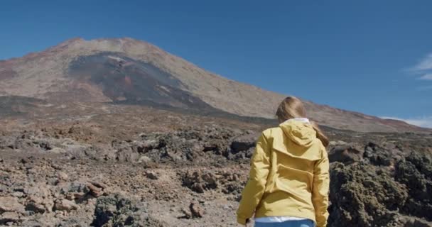 Teide, Tenerife, Canary islands, Spain. Young woman hiking along the volcanic sand among lava rocks in a huge crater of Teide volcano — Stock Video