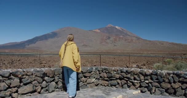 Teide, Teneryfa, Wyspy Kanaryjskie, Hiszpania. Młoda kobieta wędrująca wzdłuż wulkanicznego piasku pośród skał lawy w ogromnym kraterze wulkanu Teide — Wideo stockowe