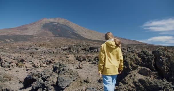 Teide, Tenerife, Isole Canarie, Spagna. Giovane donna che cammina lungo la sabbia vulcanica tra rocce laviche in un enorme cratere del vulcano Teide — Video Stock