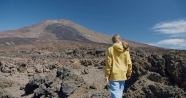 Teide, Tenerife, Kanarya Adaları, İspanya. Genç bir kadın volkanik kum boyunca volkanik volkan kraterinde lav kayaları arasında yürüyüş yapıyor..