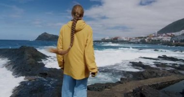 Genç bayan turist deniz kenarında eğleniyor. Tasasız kız kollarını kaldırıyor, Garachico. Tenerife. Kanarya Adaları. İspanya.