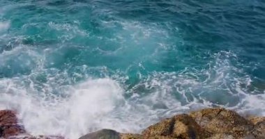 Yaklaş, okyanus dalgaları Tenerife sahillerinde ıslak taşların üzerinden köpüklü suyun üzerinde güneş ışığıyla süzülüyor. Kanarya Adaları, İspanya.