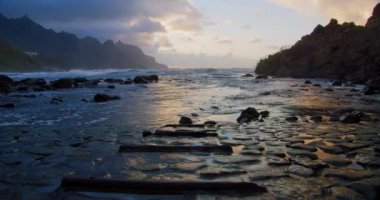 Beautiful sunset light and sunbeams at Benijo Beach in Tenerife, Canary Islands, Spain. Steps go into the water, ocean. Cinematic colorful view on Playa de Benijo.
