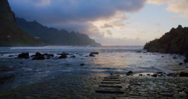 Beautiful sunset light and sunbeams at Benijo Beach in Tenerife, Canary Islands, Spain. Steps go into the water, ocean. Cinematic colorful view on Playa de Benijo.