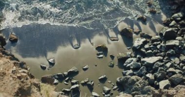 Beautiful wild ocean waves crashing on rocky coast seashore beach. Foamy deep blue sea water seascape. Ocean vacation. Tropical islands.