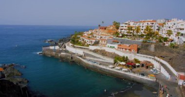 Tenerife, Canary Island, town with buildings Puerto de Santiago, Playa de Santiago. View of black rocky beach and natural pool in Atlantic Ocean. Nobody.