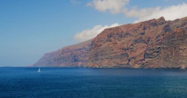 Los Gigantes, Tenerife. Canary island. Yacht sailing on open ocean at sunny day . Sun shine over white sail boat at ocean bay. Sailboat cruise at serene seascape. Amazing ship racing at summer