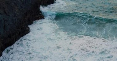 Big ocean waves at sunset. Aqua blue waves crash into black lava rock shore. Birds eye view. Tenerife. Canary Islands, Spain. Europe. Nobody.