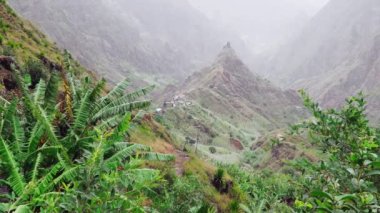 Idyllic kırsal dağ manzarası. Çim ve muz bitkileriyle kaplı engebeli dağ sırtı vadiye yayılıyor. Yeşillik vadideki yerel köy. Santa Antao Adası, Cape Verde, Cabo Verde.