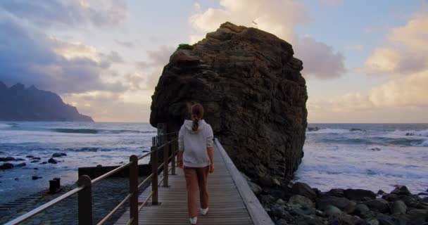 女游客在一座木制的桥上行走 这座桥来自美丽的蓝色火山岩海滩 夕阳西下 海浪汹涌 Tenerife 加那利群岛 西班牙 慢动作放松镜头 — 图库视频影像