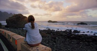 Tenerife. Canary Islands. Anaga rural park. Young woman tourist on shore enjoing marine views. Rocky seacoast beach. Happy girl looking at Ocean. Summer relaxing on sea resort. Sea line beach
