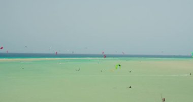 Kiters train. Surfing on a kiteboard on the sea on shallow blue water of Atlantic ocean nature landscape. Extreme sports in Playa la Lajita, Fuerteventura, Canary Islands, Spain. Unrecognizable people