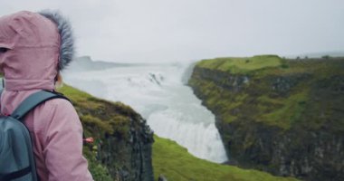Gullfoss Şelalesi 'ne bakan turist kadın. İzlanda' nın en ünlü eğlence ve dönüm noktası..