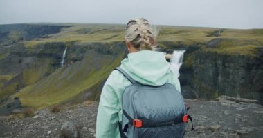 Sırt çantalı kadın İzlanda 'da Haifoss şelalesinin keyfini çıkarıyor..