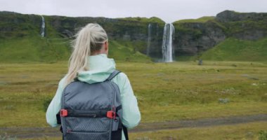 Sırt çantalı kadın Seljalandsfoss Şelalesi İzlanda 'ya bakıyor.