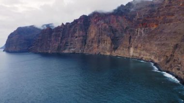 Tenerife 'deki Los Gigantes uçurumlarının havadan görünüşü. Büyük kayaların üzerinden uçmak. Sakin Atlantik Okyanusu 'nun muhteşem manzarası. Cennet muhteşem adasına bir gezi. Volkanik deniz manzarasında yolculuk. Kamera hareket ediyor