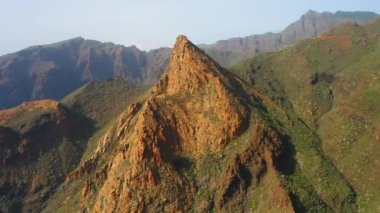 Batan güneşin ışığında inanılmaz güzel, keskin uçurumlar. Kayaların sırtları baharda yeşil bitki örtüsünün üzerinde yükselir. Dağ Risco Blanco. Her yere gidin. Tenerife, Kanarya Adaları, İspanya