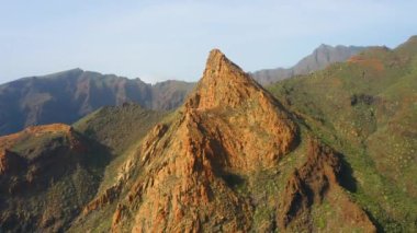 Batan güneşin ışığında inanılmaz güzel, keskin uçurumlar. Kayaların sırtları baharda yeşil bitki örtüsünün üzerinde yükselir. Dağ Risco Blanco. Her yere gidin. Tenerife, Kanarya Adaları, İspanya