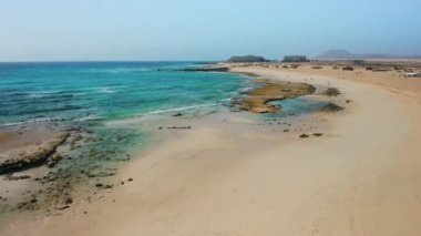 Grandes, Corralejo 'yu oynuyor. Güzel turkuaz okyanus suyu ve beyaz kum. Şeffaf dalgalar. Turist beldesi. Seyahat güzergahı. Corralejo Büyük Plaj Ulusal Parkı, Fuerteventura, Kanarya