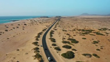 Corralejo, Fuerteventura, Kanarya Adaları, İspanya 'daki kum tepeleri boyunca asfalt yol. Atlantik Okyanusu boyunca otoban manzarası. Doğal Park. Seyahat sıkıntısı. Her yere gidin. Kimse..