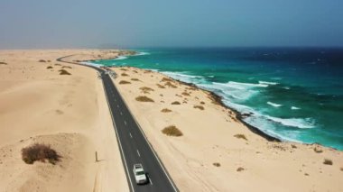 Atlantik Okyanusu kıyı şeridi, sahil boyunca asfalt yol, Playa Alzada, sörf kırılma noktası, kum tepeleri manzarası, Corralejo 'daki vahşi çöl manzarası. Turkuaz su. Özgürlüğü hisset