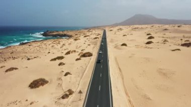 Atlantik Okyanusu kıyı şeridi, sahil boyunca asfalt yol, Playa Alzada, sörf kırılma noktası, kum tepeleri manzarası, Corralejo 'daki vahşi çöl manzarası. Turkuaz su. Özgürlüğü hisset