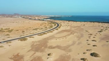 Atlantik okyanusu gök mavisi dalgaları. Otoyol manzaralı, Corralejo kumsalında, kenar mahallelerde. Şehrin havadan manzarası. Yol trafiği ve körfez suyu. Resort şehir manzarası. Fuerteventura, Kanarya Adaları