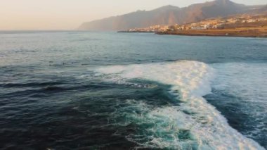 Mavi denizin dalgalı su yüzeyi ve gün batımında Tenerife adasının sahillerinde esen güçlü rüzgar yüzünden oluşan dalgalar. Los Gigantes tatil beldesi yakınlarında yoğun sis ile kaplı dev dağ sıraları.