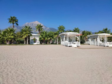 Tekirova, Antalya, Türkiye - 11 Mayıs 2021: Türkiye 'nin Kemer kentindeki Tekirova' da şemsiye ve şezlonglarla kumsaldaki güverte sandalyeleri