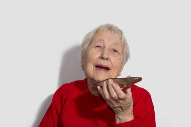 Sesi tanıma işlevini cep telefonunda kullanan çekici yaşlı bir kadın. Elektronik alet tutan, sesli mesaj gönderen ya da internetten mesaj gönderen son sınıf öğrencisi bir kadın.