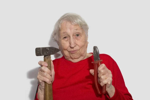 Retrato engraçado de mulher sênior segurando martelo e alicates em sua mão isolado em branco — Fotografia de Stock