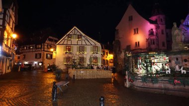 Eguisheim, Alsace, Fransa - 30 Aralık 2021: Turistler renkli yarı ağaçlı evler arasında Grand Rue caddesi boyunca yürüyorlar