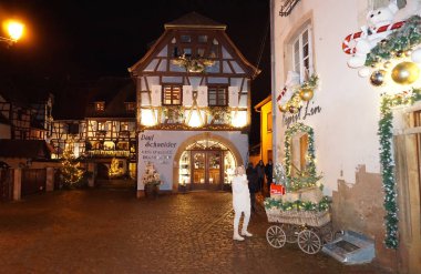 Eguisheim, Alsace, Fransa - 30 Aralık 2021: Turistler renkli yarı ağaçlı evler arasında Grand Rue caddesi boyunca yürüyorlar