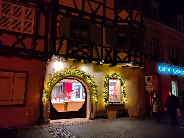 Eguisheim, Alsace, Fransa - 30 Aralık 2021: Turistler renkli yarı ağaçlı evler arasında Grand Rue caddesi boyunca yürüyorlar