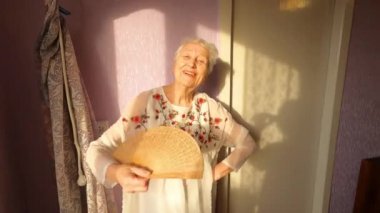 Mutlu gülümseyen komik son sınıf öğrencisi kadın evde dans ediyor.