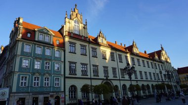 Wroclaw, Polonya - 17 Nisan 2022: Polonya 'daki Wroclaw Meydanı' nın merkezinde saatle eski belediye binasının yakınına giden insanlar