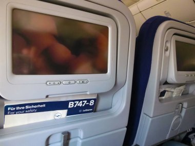 Frankfurt am Main, Germany - May 09, 2022: The blue screens display on airplane seat monitor and interior of Boeing 747 by Lufthansa before the flight