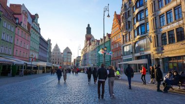 Wroclaw, Polonya - 17 Nisan 2022: Polonya 'daki Wroclaw Meydanı' nın merkezinde saatle eski belediye binasının yakınına giden insanlar