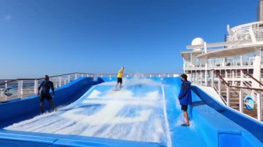 Miami, USA - April 29, 2022: People surfing on the Flow Rider attraction. The passengers at pool games, bars, outdoor fun, entertainment and innovative activities attract new cruisers every year.