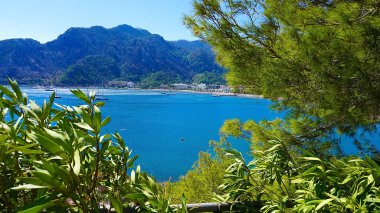 Marmaris Town 'daki Icmeler Sahili manzarası. Türkiye 'nin Akdeniz kıyısında yaz manzarası. Koy manzarası ve çam dalları arasında dağlar