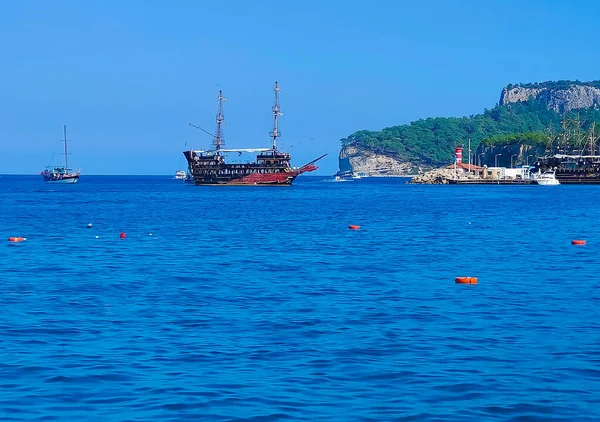 Vintage mast wooden sailing ship for sea tours. Touristic pirate ship in port. Marina in in resort city Kemer, Turkey. Old harbour in Turkey.