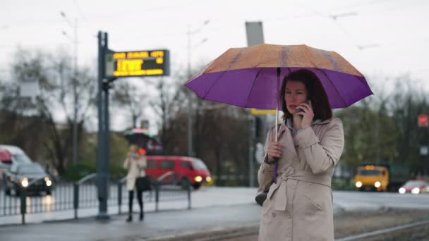 Woman talking on phone under umbrella — Stock Video