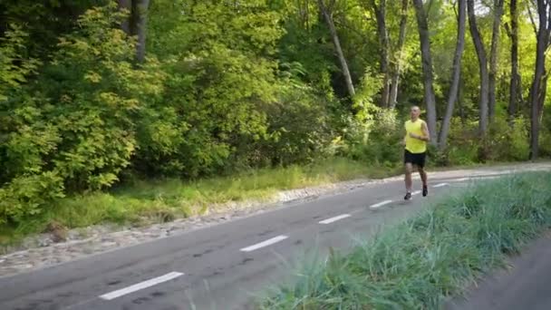 Fit man running near forest in slow motion — Stock video