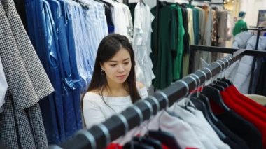 Moda mağazasında kıyafet arayan Asyalı bir kadın.