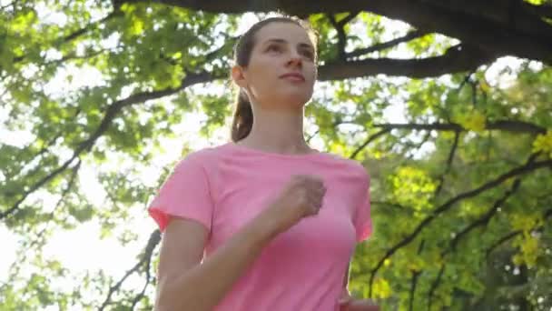 Woman running under trees in slow motion — Stock Video