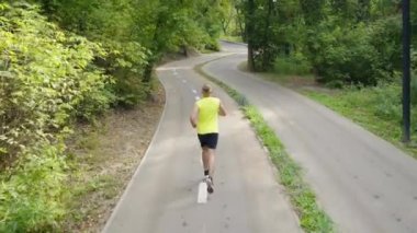 Ağaçlar arasındaki boş yolda koşan bir adam